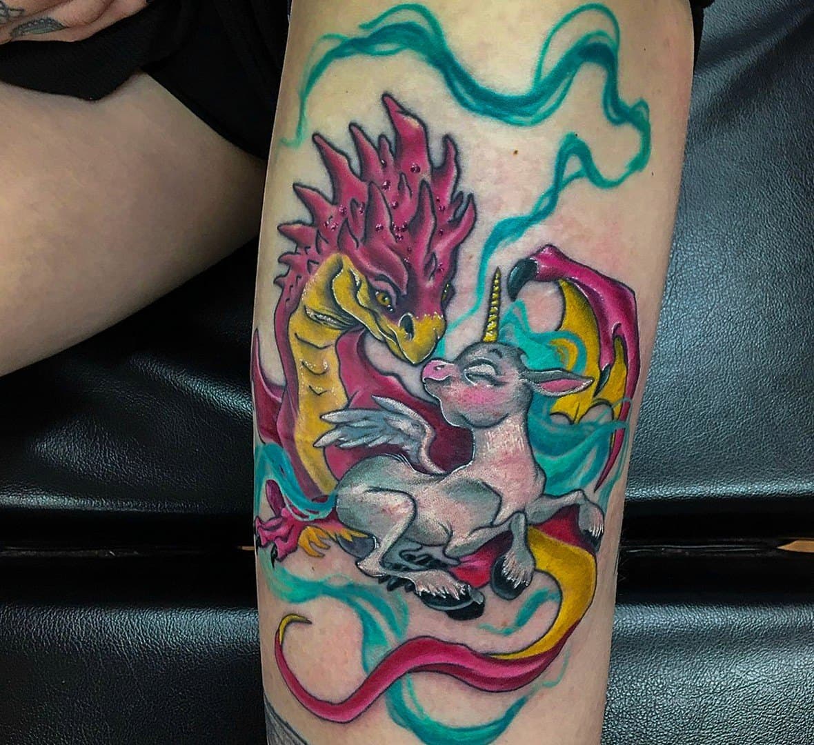 Colour tattoo of a unicorn wrapped in swirling pink and teal smoke