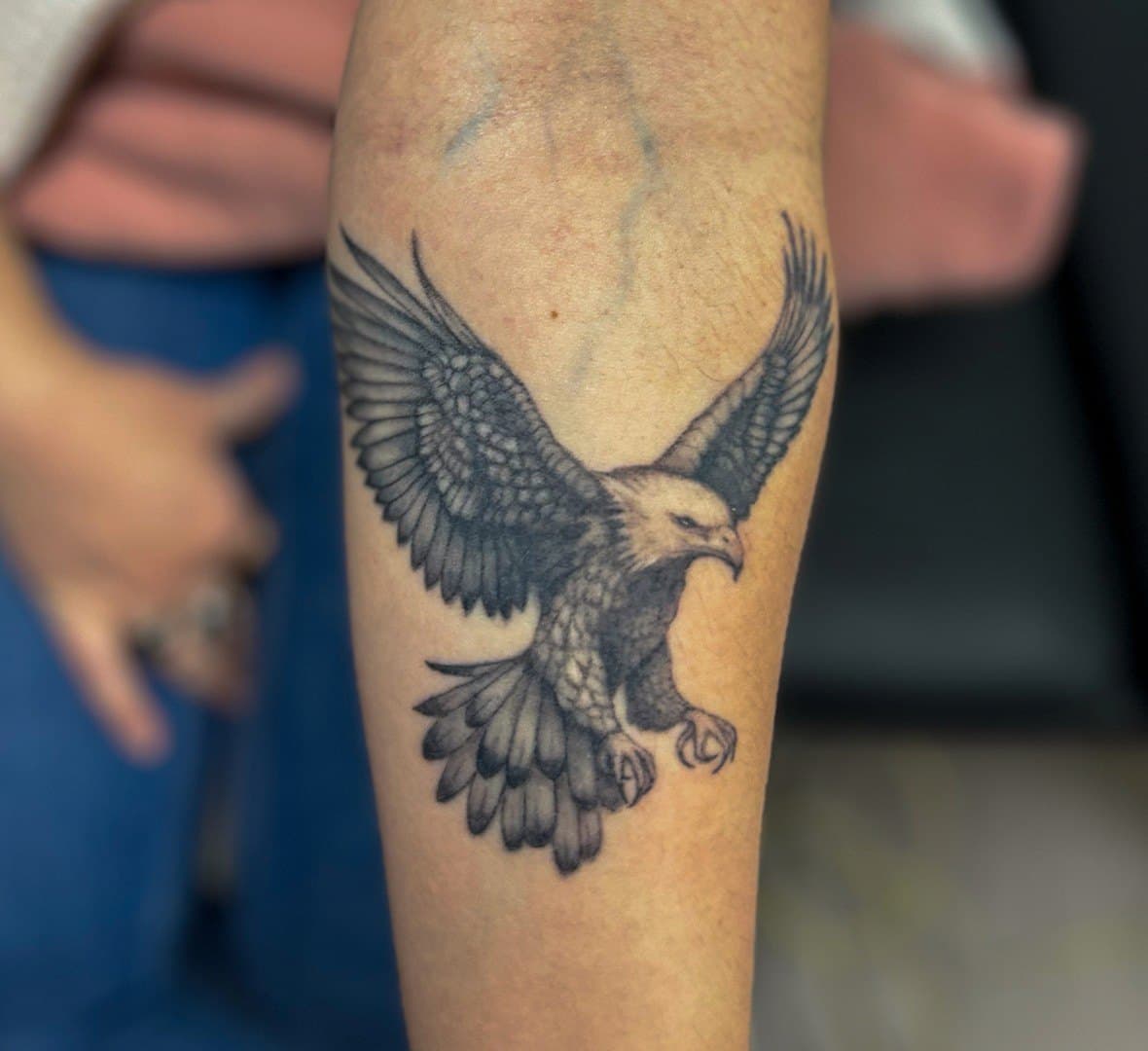 Black and grey tattoo of an eagle with spread wings on a forearm