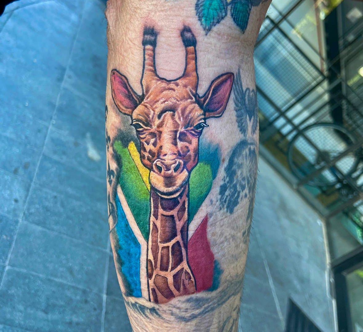 Colour tattoo of a giraffe with rainbow brush strokes on a calf