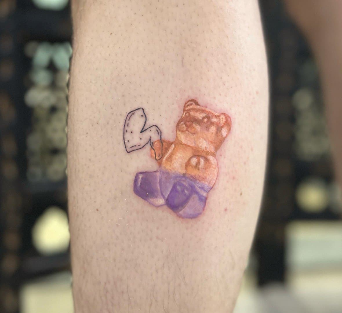 Colour tattoo of an orange and purple gummy bear on an upper arm