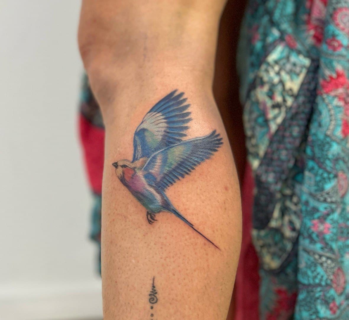 Colour tattoo of a blue swallow in flight on a calf