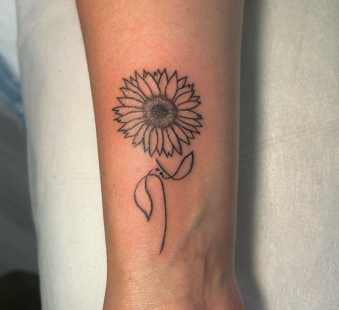 Fine line tattoo of a sunflower on a lower leg